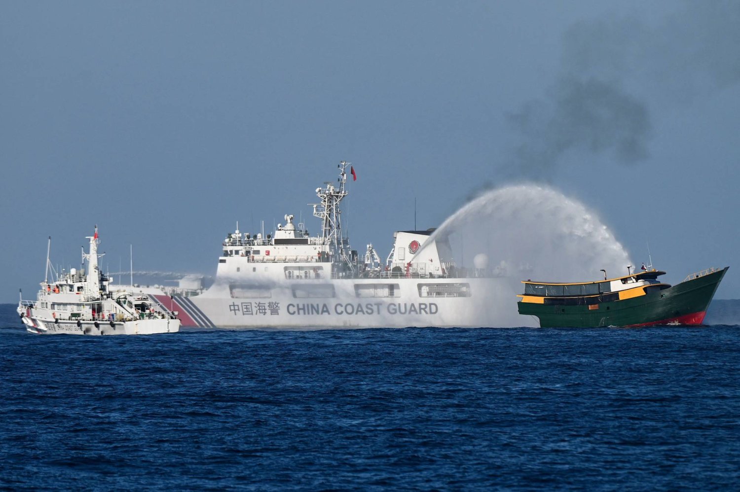 سفينة لقوة خفر السواحل الصينية ترش الماء على مركب فلبيني في منطقة متنازع عليها ببحر الصين الجنوبي (أ.ف.ب)