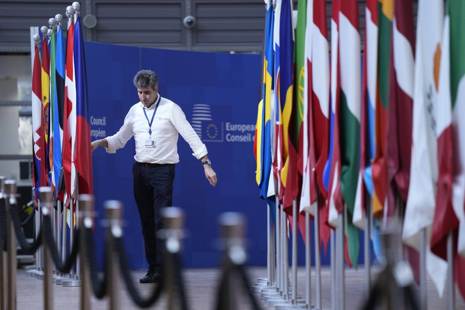 عامل يرتّب أعلام الدول الأعضاء في الاتحاد الأوروبي قبل قمة سابقة في بروكسل (أرشيفية - أ.ب)