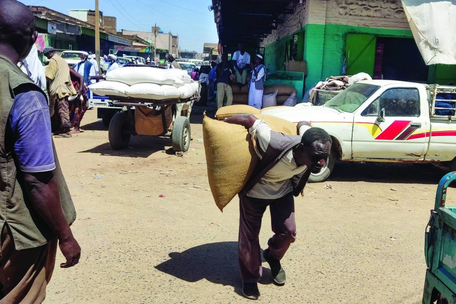 
سوداني يحمل كيساً من الحبوب يوم الأربعاء في مدينة القضارف شرق السودان (أ.ف.ب)