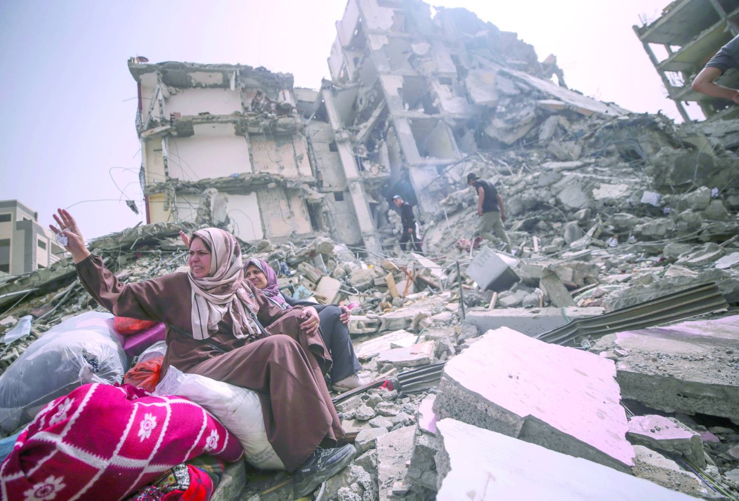 
امرأتان تجلسان وسط الركام بعد عودتهما إلى «مخيم النصيرات» بعد انسحاب الجيش الإسرائيلي وسط قطاع غزة أمس (إ.ب.أ)