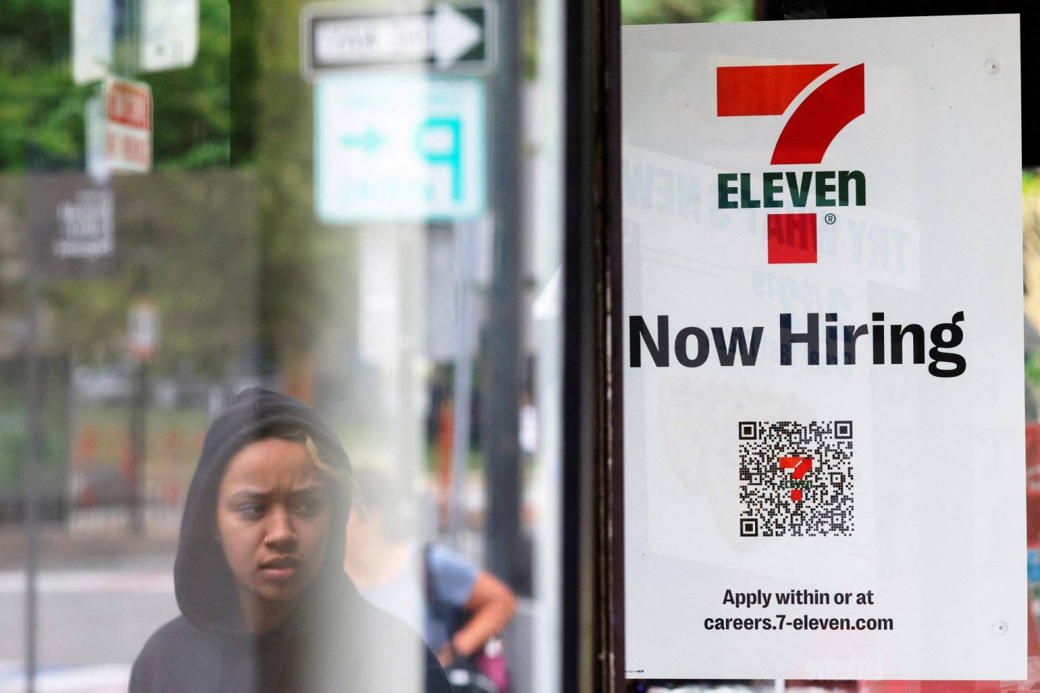 لافتة على نافذة متجر «إيلفن-7» كتب عليها «نوظف الآن» في كمبردج بماساتشوستس في الولايات المتحدة (رويترز)