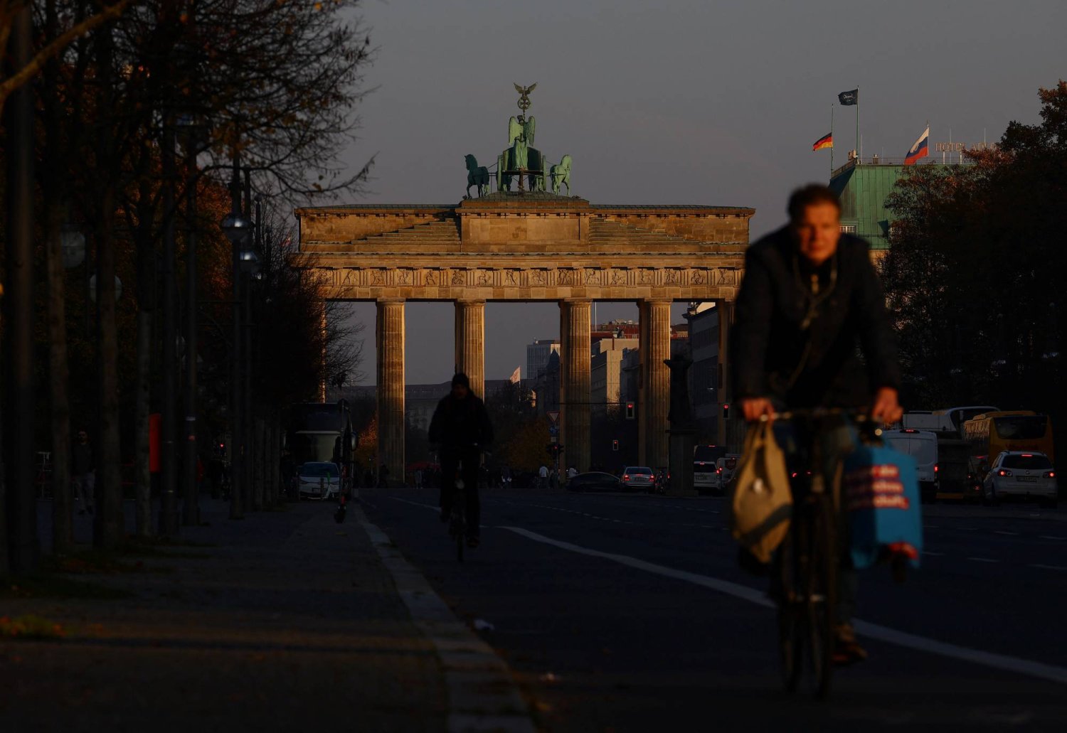 مواطنون يركبون الدراجات على الطريق أمام بوابة براندنبورغ في وسط برلين بألمانيا (رويترز)