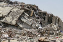 فلسطينيون يبحثون عن أشياء يمكن إنقاذها بين أنقاض مبنى سكني دمرته الغارات الإسرائيلية (رويترز)