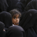 طفلة يمنية بين مجموعة نساء ينتظرن الحصول على مساعدات غذائية (إ.ب.أ)