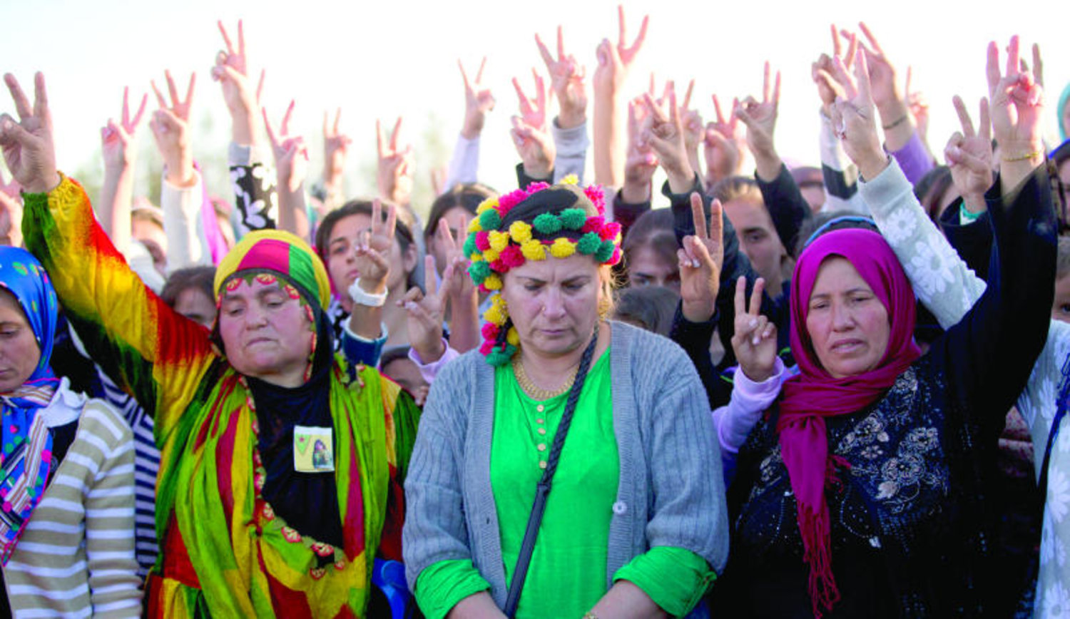 كرديات على الحدود التركية السورية يسرن في مسيرة حزنا على إحدى المقاتلات الكرديات التي قتلت في كوباني أمس (أ.ب)