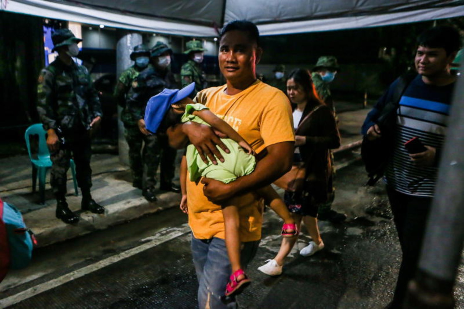 رجل وطفله في أحد نقاط الجيش وسط حالة إغلاق للعاصمة الفلبينية (إ.ب.أ)
