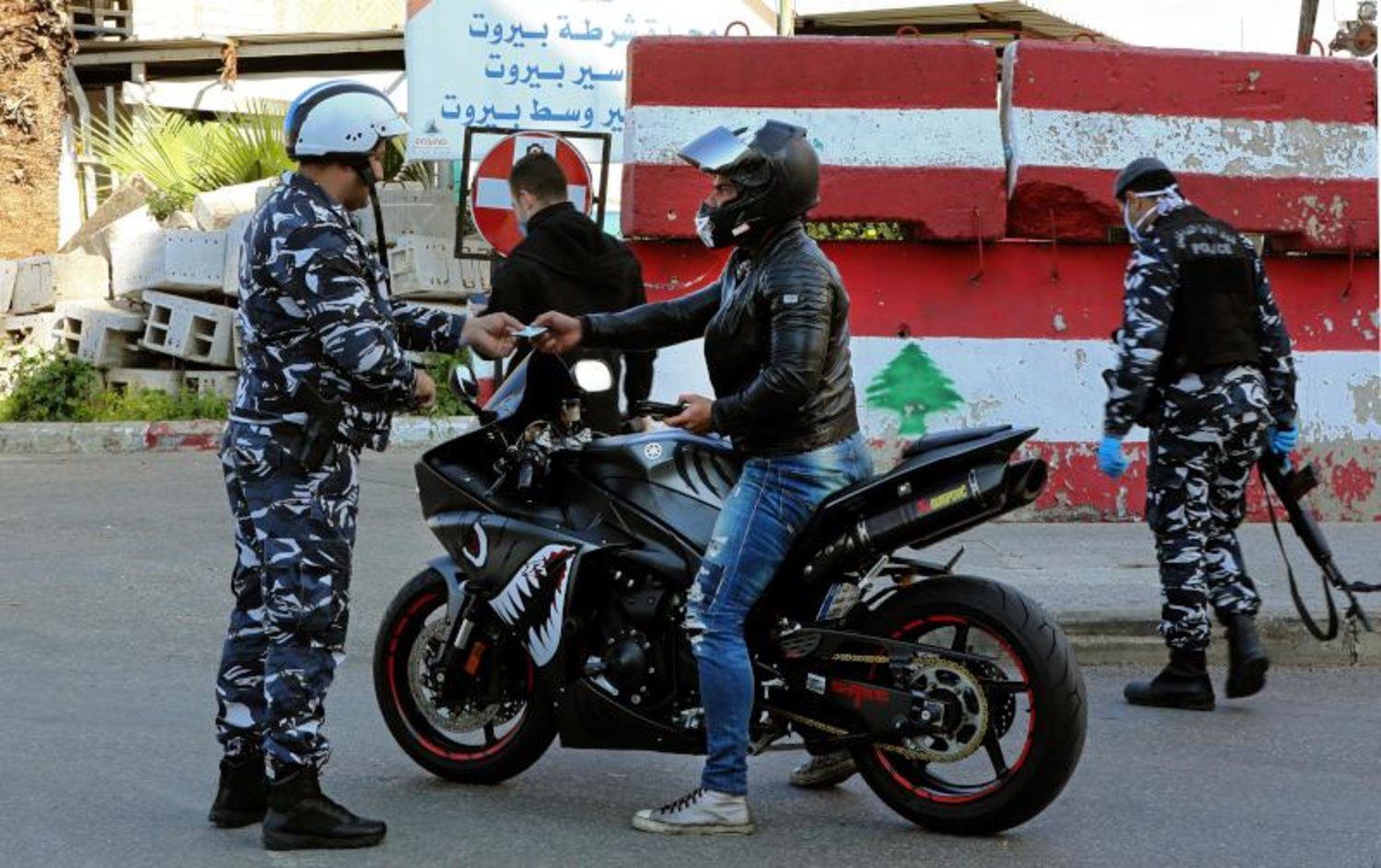 ضابط شرطة يغرّم قائد دراجة نارية في بيروت لخرقه القرارات الاحترازية لمكافحة كورونا (أ.ف.ب)