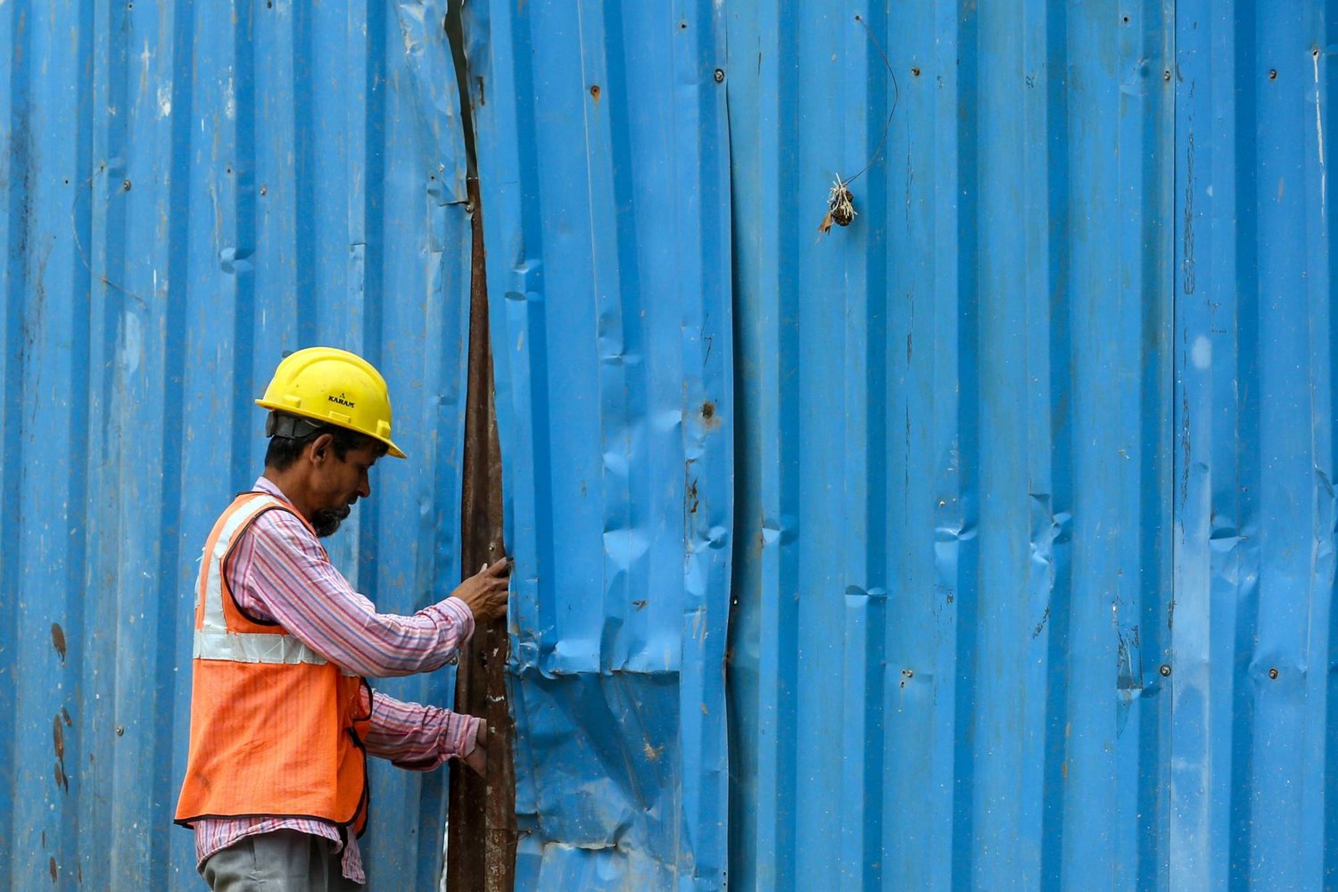 عامل هندي يغلق بوابة موقع تحت الإنشاء في يوم العمال العالمي في ضواحي مومباي 1 مايو (إ.ب.أ)