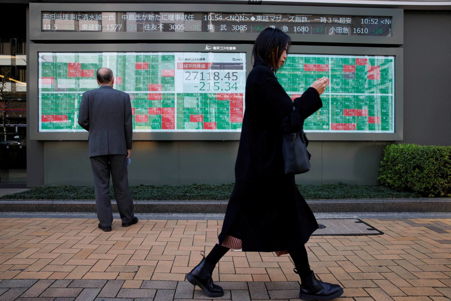 أشخاص أمام لوحة إلكترونية تعرض أداء مؤشر نيكي وأسعار الأسهم في طوكيو، اليابان - رويترز 