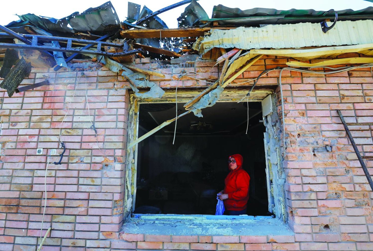 
امرأة تنظر من داخل منزلها المدمَّر بفعل القصف في مدينة هورليفيكا بإقليم دونيتسك أمس (رويترز)
