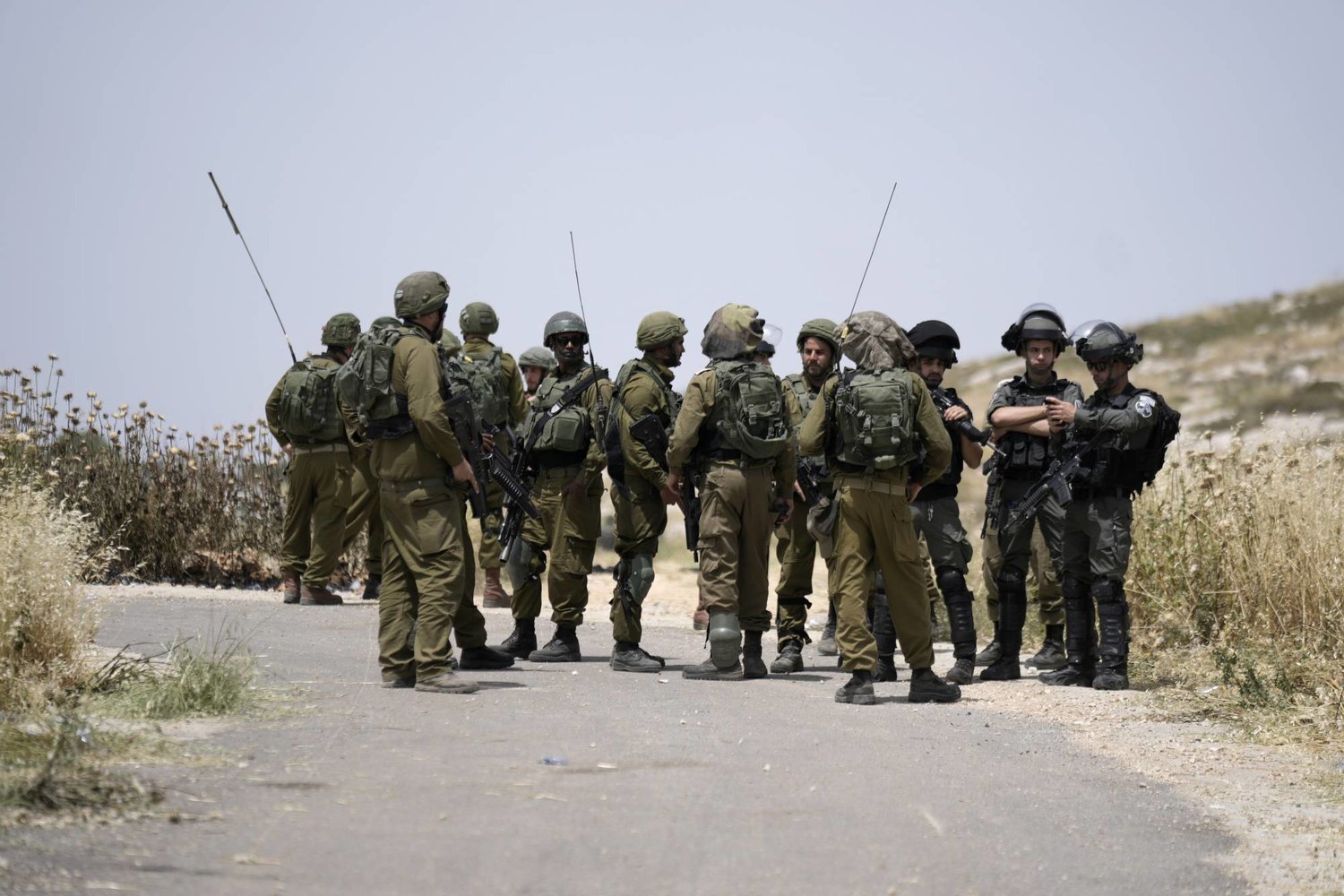 جنود إسرائيليون وشرطة الحدود حيث قام المستوطنون الإسرائيليون بإحراق سيارات فلسطينية وحقول قمح في قرية المغير بالقرب من مدينة رام الله بالضفة الغربية في 26 مايو الماضي (أ.ب)
