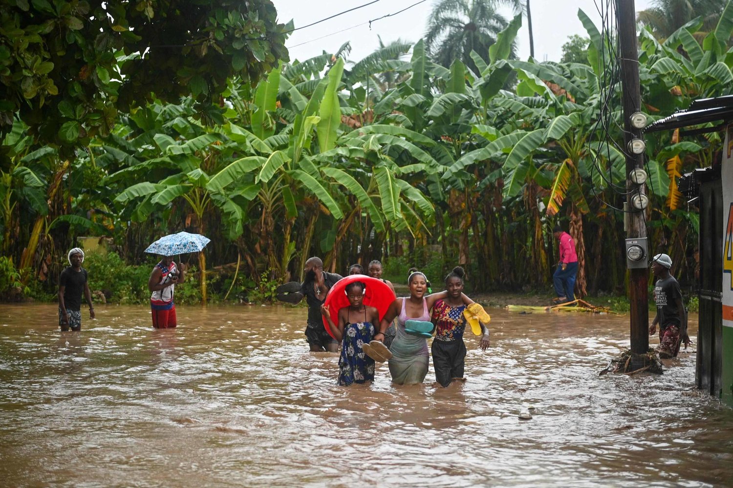 أشخاص يسيرون في طريق غمرته مياه الفيضانات في هايتي (أ.ف.ب)