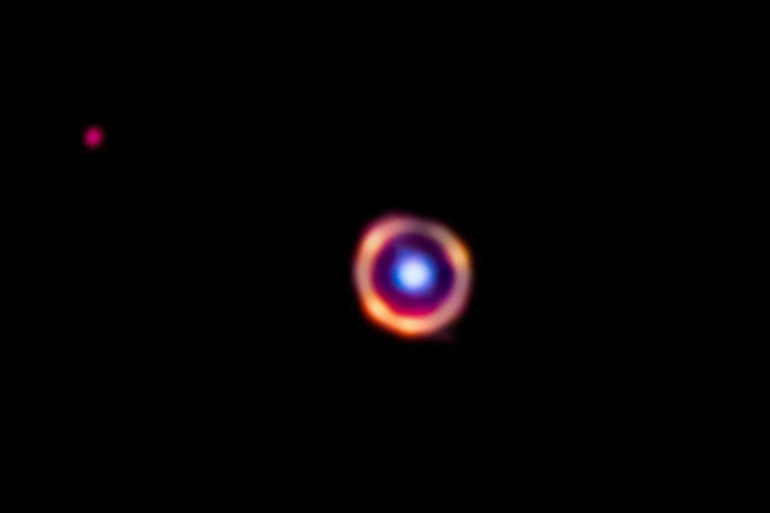 صورة تلسكوب «جيمس ويب» لمجرة «SPT0418 - 47» باللون الأحمر... وتم تمييز الجزيئات العضوية باللون البرتقالي بينما توجد مجرة أمامها باللون الأزرق (ناسا)