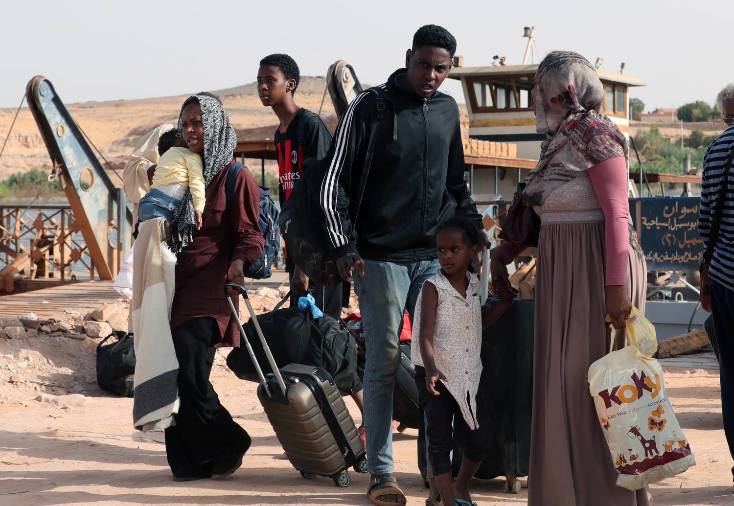 لاجئون سودانيون يحملون أمتعتهم بعد عبورهم إلى مصر (إ.ب.أ)