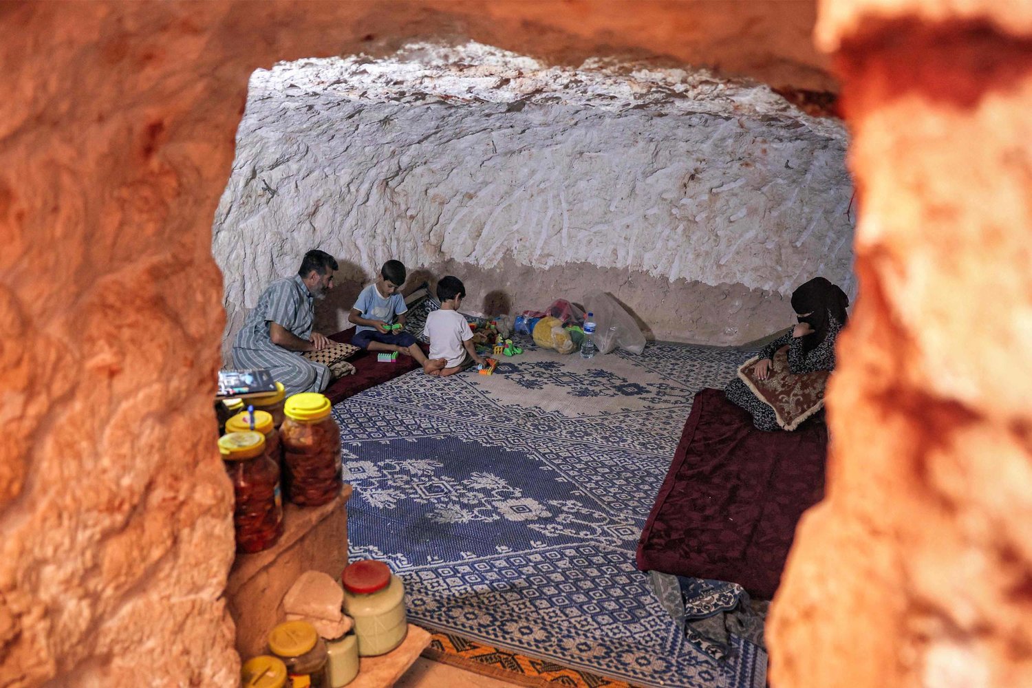 يجلس أحمد خليل مع عائلته في كهف حفره بالصخر