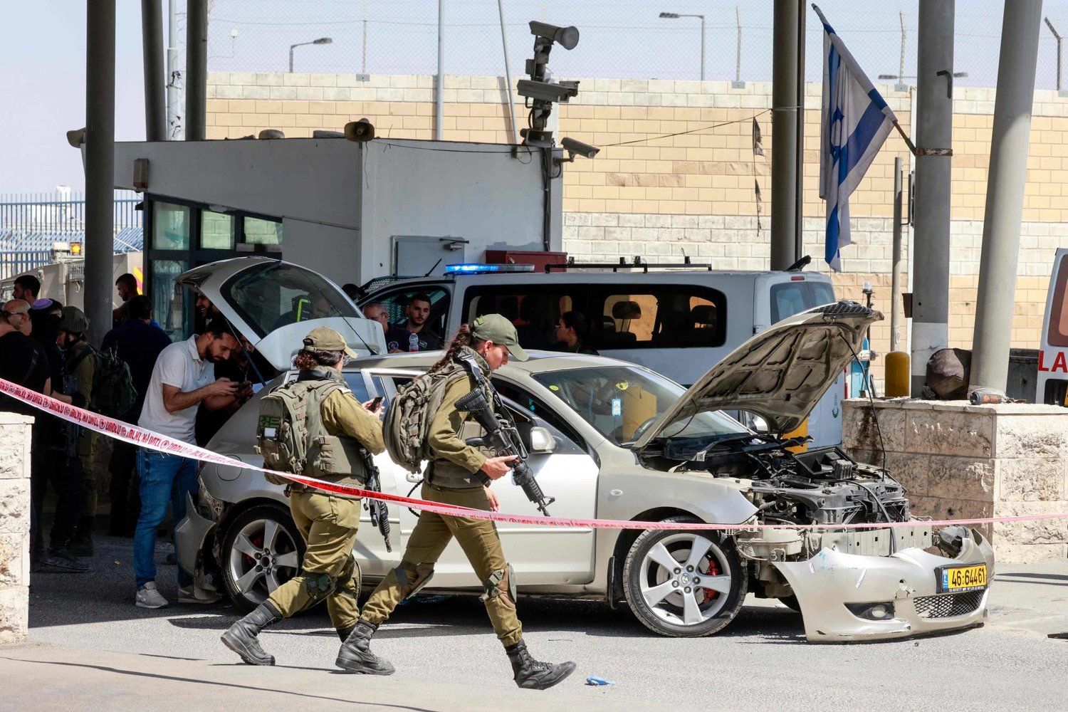 جنود إسرائيليون يحاصرون سيارة مدمرة عند حاجز قلنديا بالقرب من القدس (أ.ف.ب)