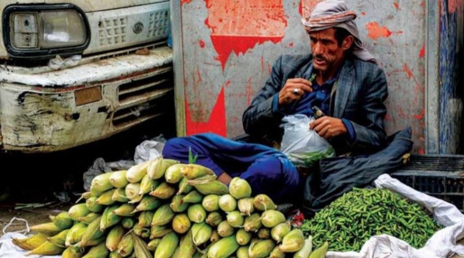 يمني في صنعاء يفترش الشارع لبيع بضاعته من الذرة والبازلاء (أ.ف.ب)