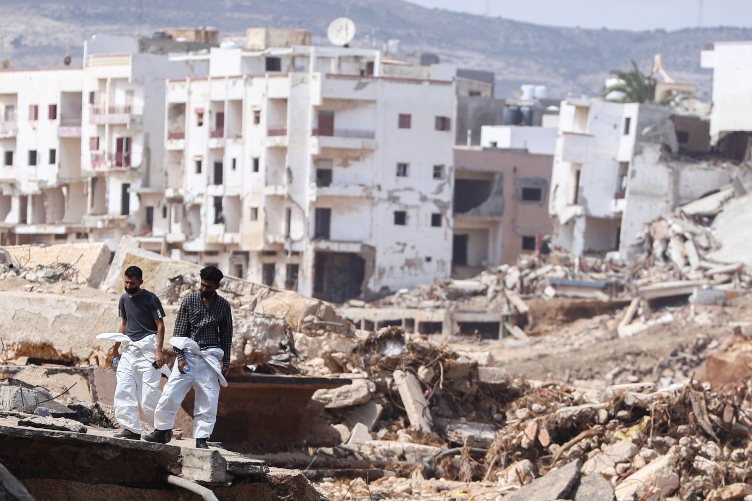 متطوعان يقفان وسط الدمار في درنة (رويترز)