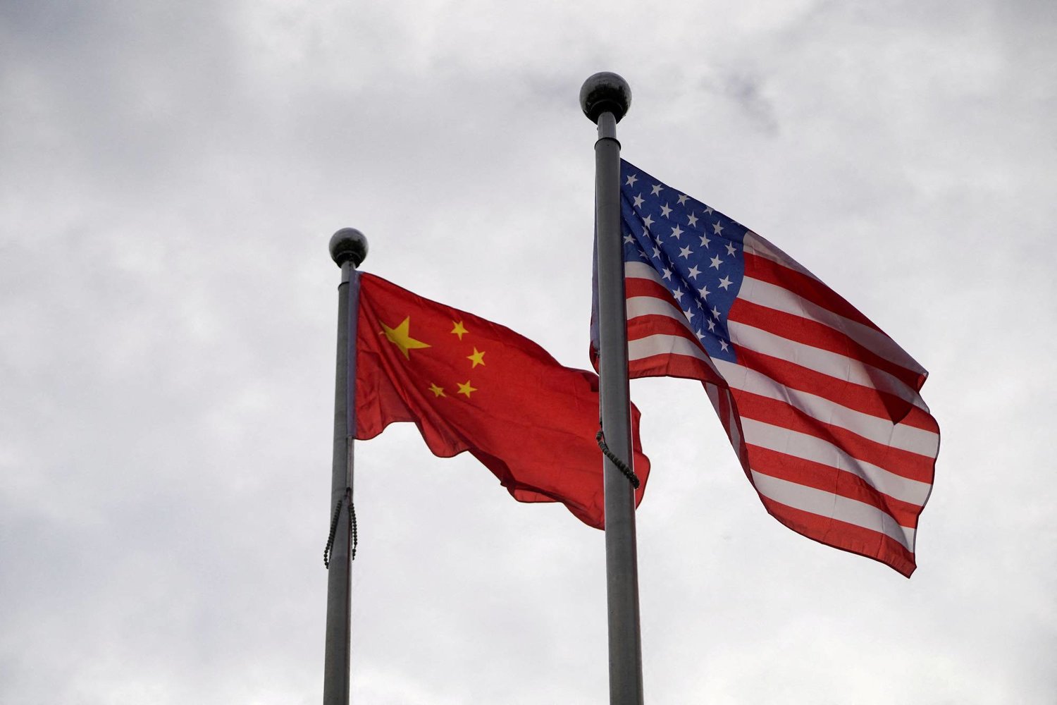 علما الولايات المتحدة (يمين) والصين يرفرفان خارج مبنى شركة في شنغهاي بالصين في 16 نوفمبر 2021 (رويترز)
