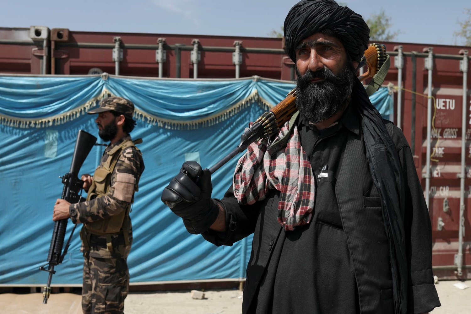 مقاتلو «طالبان» يقفون للحراسة بينما ينتظر الناس استلام أكياس الأرز كجزء من المساعدات الإنسانية التي أرسلتها الصين في مركز توزيع في كابول - أفغانستان (رويترز)