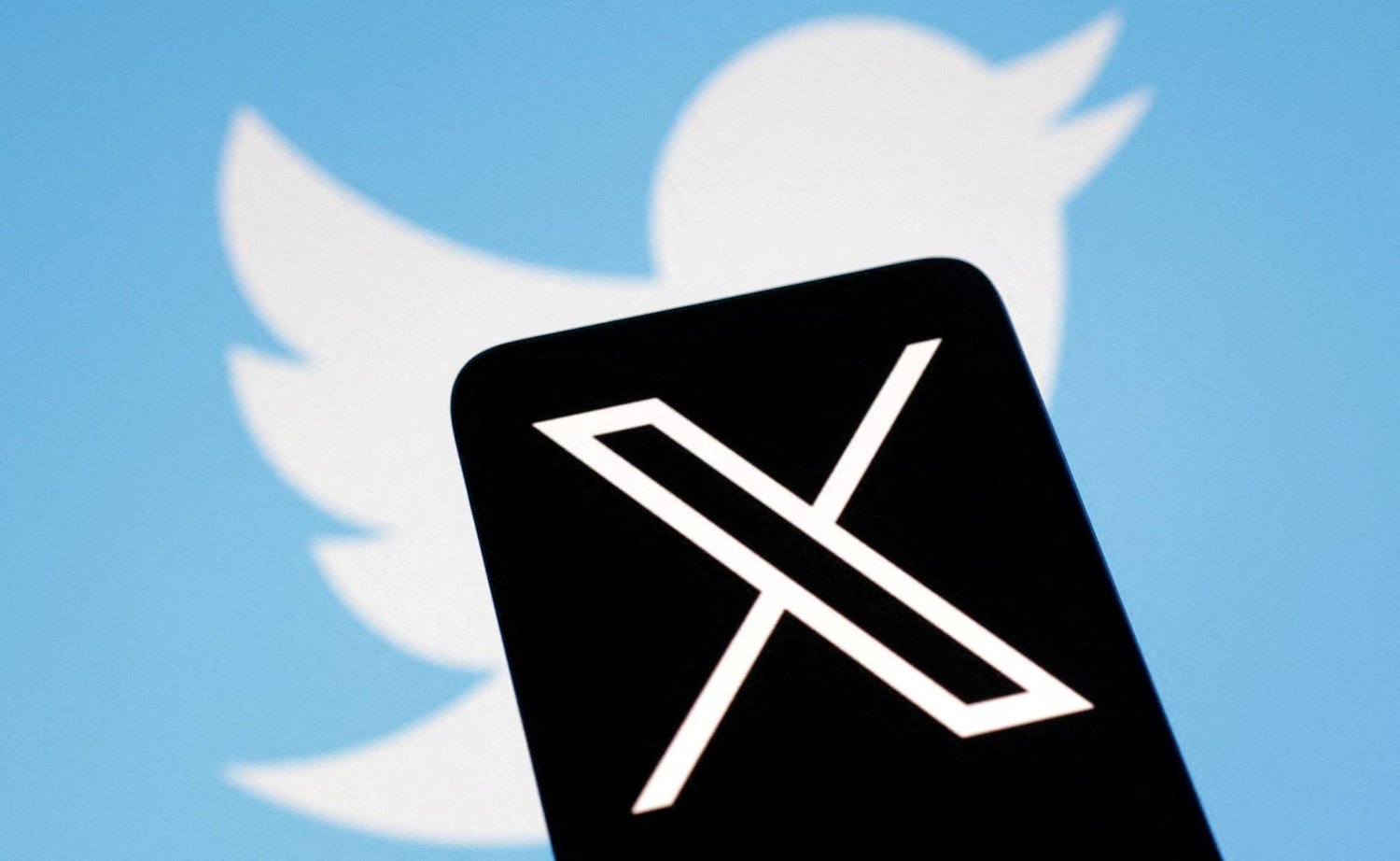 شعار منصة «إكس» يظهر أمام شعار «تويتر» (رويترز)