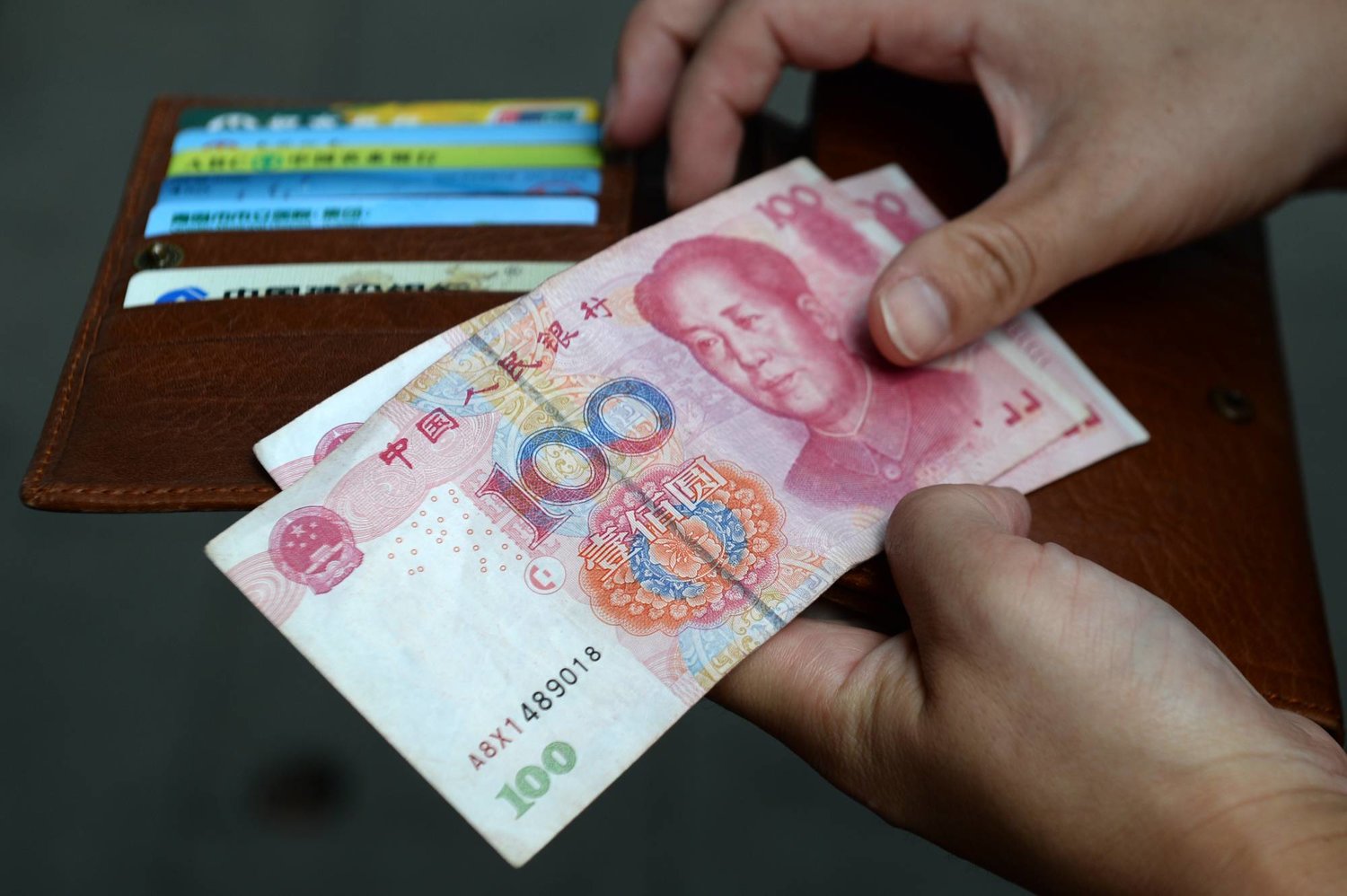 امرأة تحمل أوراقاً نقدية من اليوان الصيني (وكالة الأنباء الألمانية)