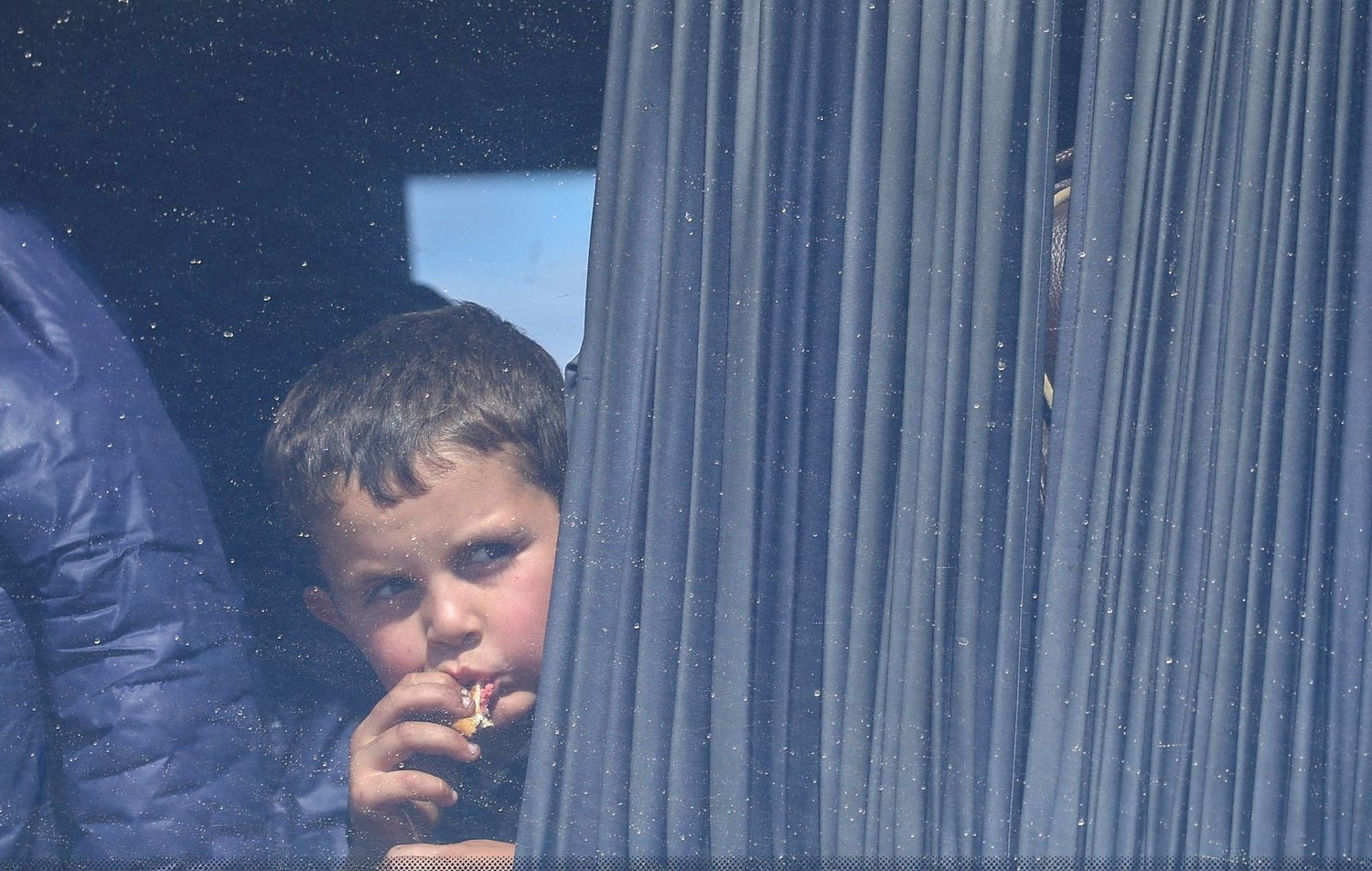 طفل ينظر من شباك حافلة لاجئين أرمن في طريقها إلى أرمينيا الثلاثاء (رويترز)