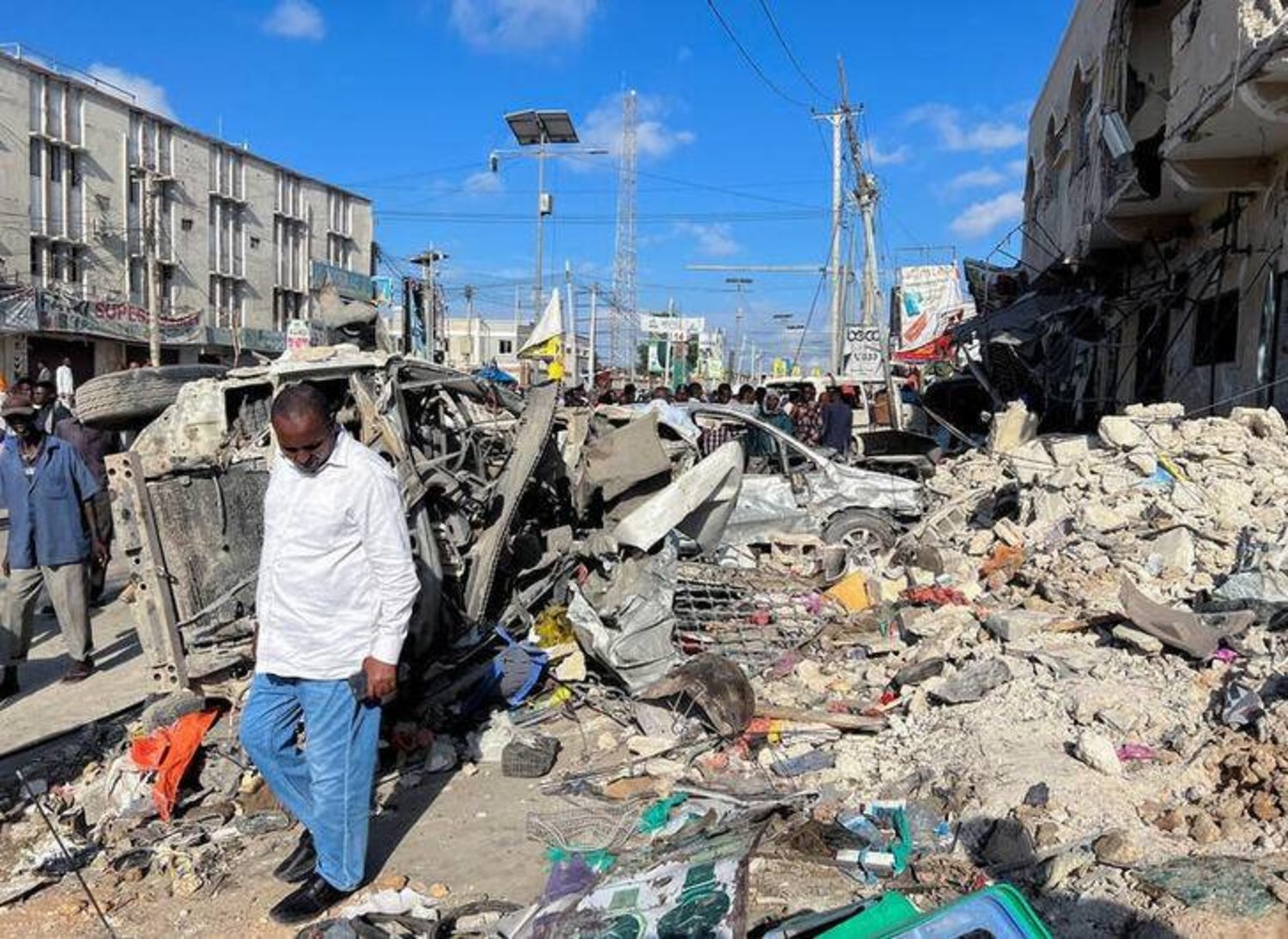رجل يسير بجوار حطام سيارات مدمرة بالقرب من أنقاض مبنى في مكان انفجار بمقديشو الصومال في 30 أكتوبر 2022 (رويترز)