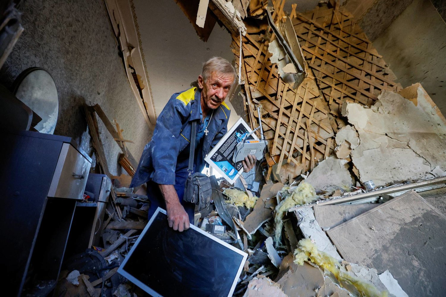 رجل يحمل ممتلكاته داخل منزل تعرض لأضرار جسيمة جراء القصف في دونيتسك (رويترز)