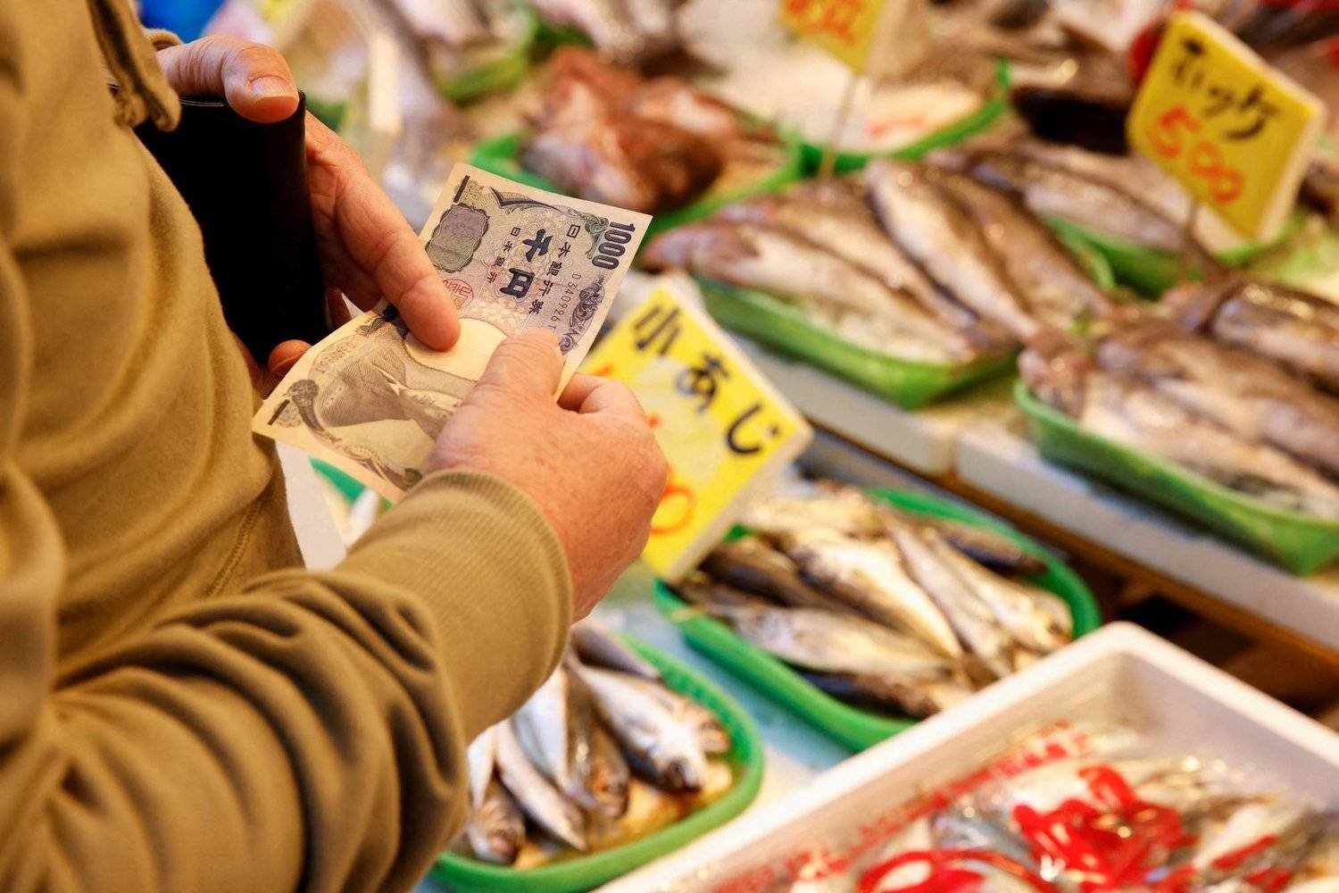 رجل يشتري سمكاً من إحدى الأسواق في طوكيو باليابان -(رويترز)