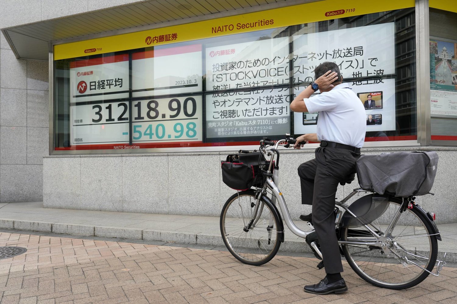 رجل على دراجة يتابع تحركات الأسهم على مؤشر «نيكي» على شاشة إلكترونية وسط العاصمة اليابانية طوكيو (إ.ب.أ)