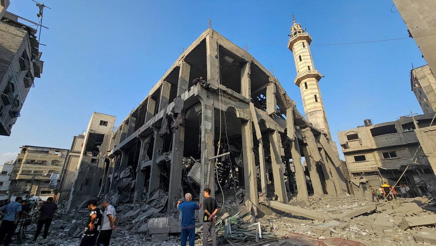 فلسطينيون يتجمعون حول بقايا مسجد دمّره القصف الإسرائيلي في قطاع غزة (رويترز)