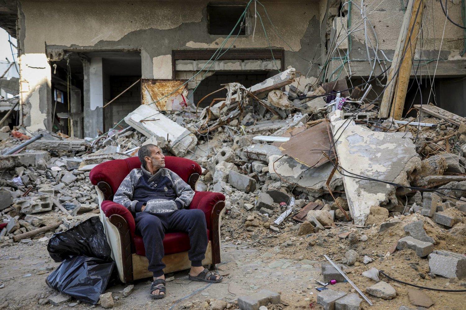  فلسطيني يجلس خارج مبنى مدمر في مدينة غزة يوم أمس الأربعاء (ا.ب)
