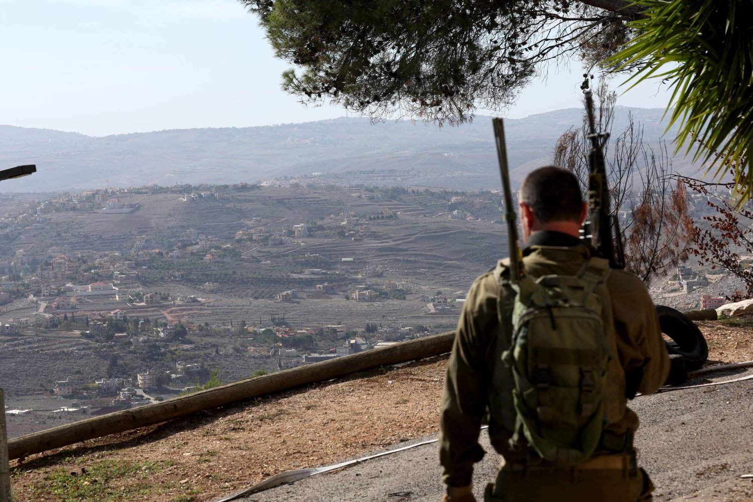 عنصر من مجموعة رد أول مسلحة تحرس «كيبوتس المنارة» على الحدود الإسرائيلية اللبنانية مع ظهور قرية حولا اللبنانية في الخلفية 30 نوفمبر 2023 (إ.ب.أ)