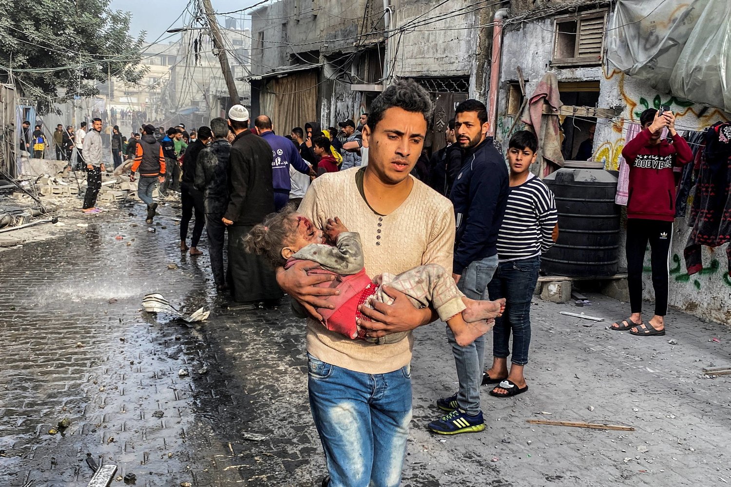 فلسطيني يحمل طفلاً جريحاً في أعقاب غارة إسرائيلية على منزل بعد انتهاء الهدنة المؤقتة بين «حماس» وإسرائيل في رفح بجنوب قطاع غزة اليوم (رويترز)