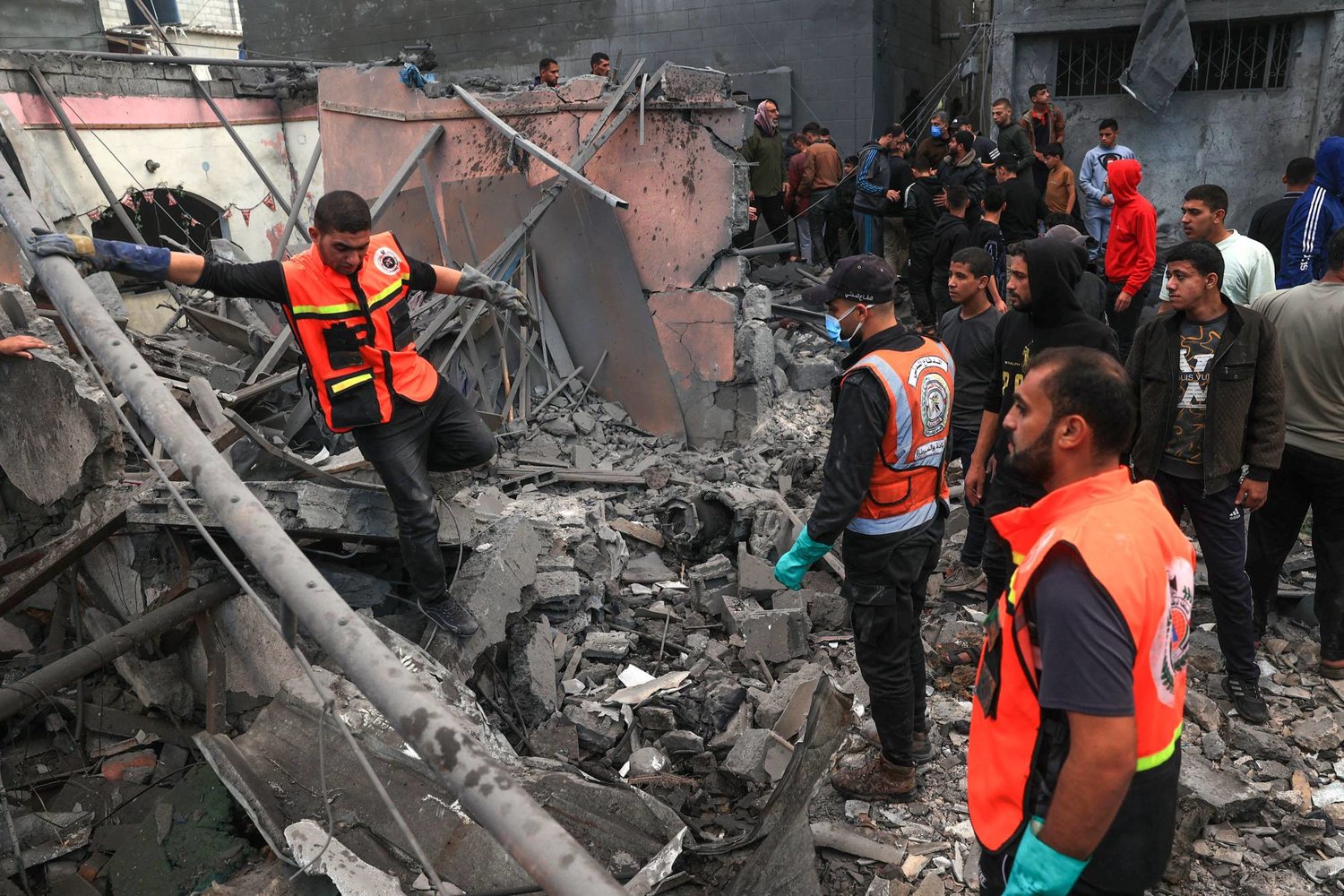 مسعفون فلسطينيون يبحثون عن ناجين تحت أنقاض مبنى بعد القصف الإسرائيلي في رفح بجنوب قطاع غزة (أ.ف.ب)