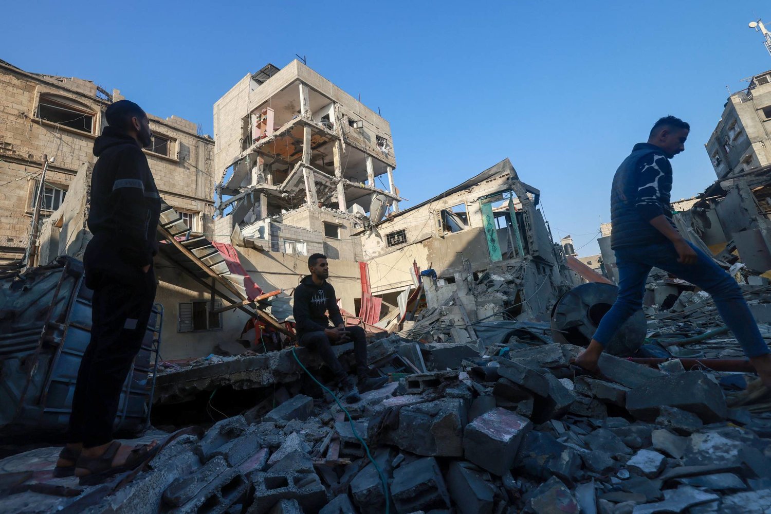 فلسطينيون يتفقدون مبنى تضرر خلال القصف الإسرائيلي في رفح جنوب قطاع غزة (أ.ف.ب)