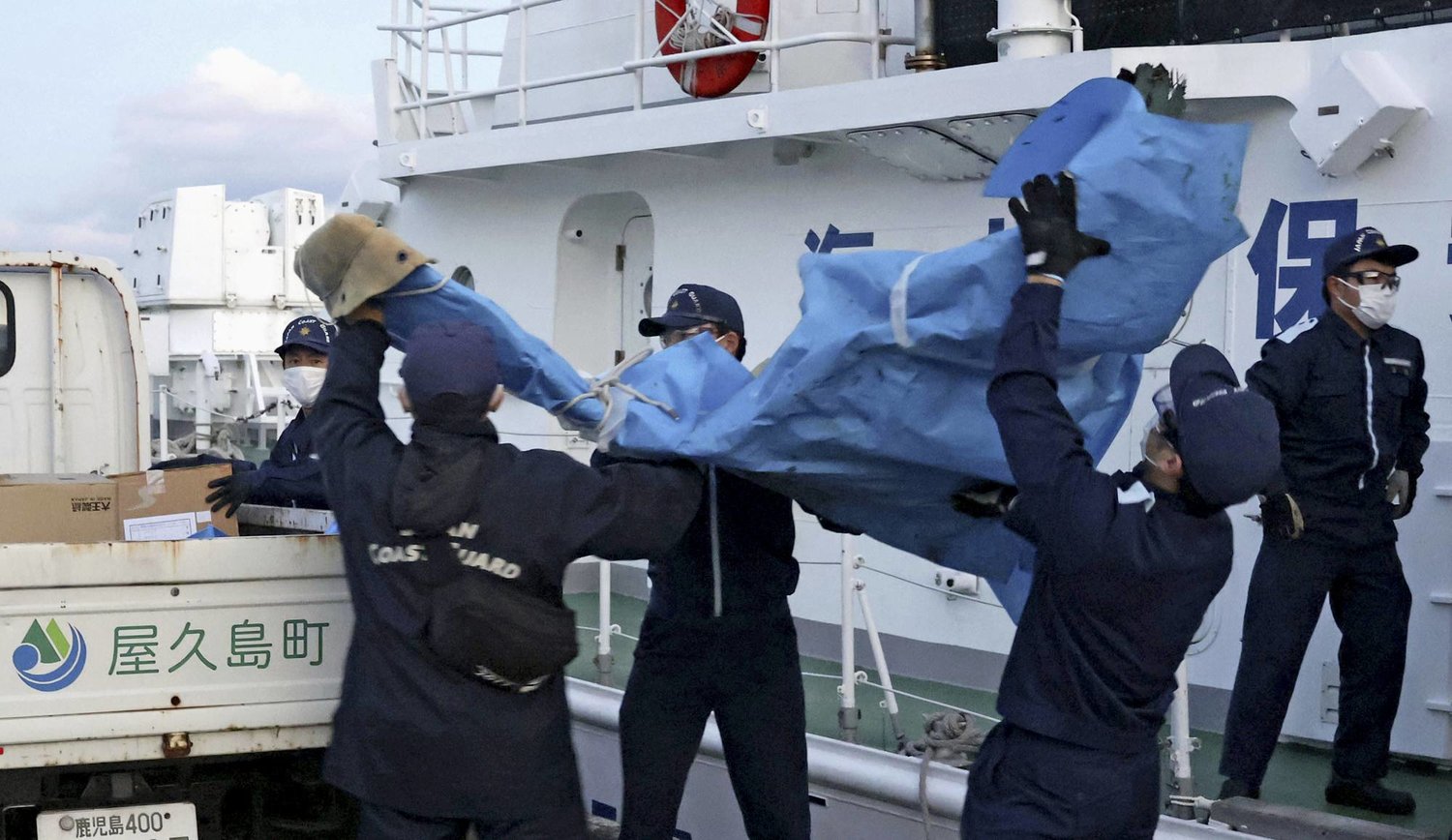 عناصر من خفر السواحل الياباني يحملون الحطام الذي يُعتقد أنه من الطائرة العسكرية الأميركية المحطّمة من طراز «أوسبري»، في ميناء في ياكوشيما، محافظة كاجوشيما، جنوب اليابان، الاثنين 4 ديسمبر 2023 (أ.ب)