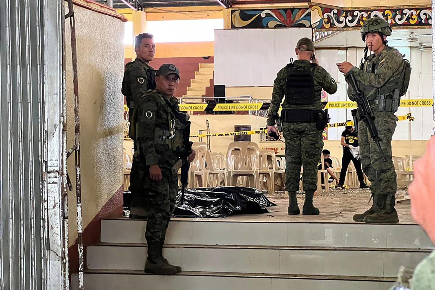 أفراد عسكريون يقفون للحراسة عند مدخل صالة للألعاب الرياضية بينما يبحث محققو الشرطة عن أدلة بعد هجوم بالقنابل في جامعة ولاية مينداناو في مراوي (الفلبين) (أ.ف.ب)