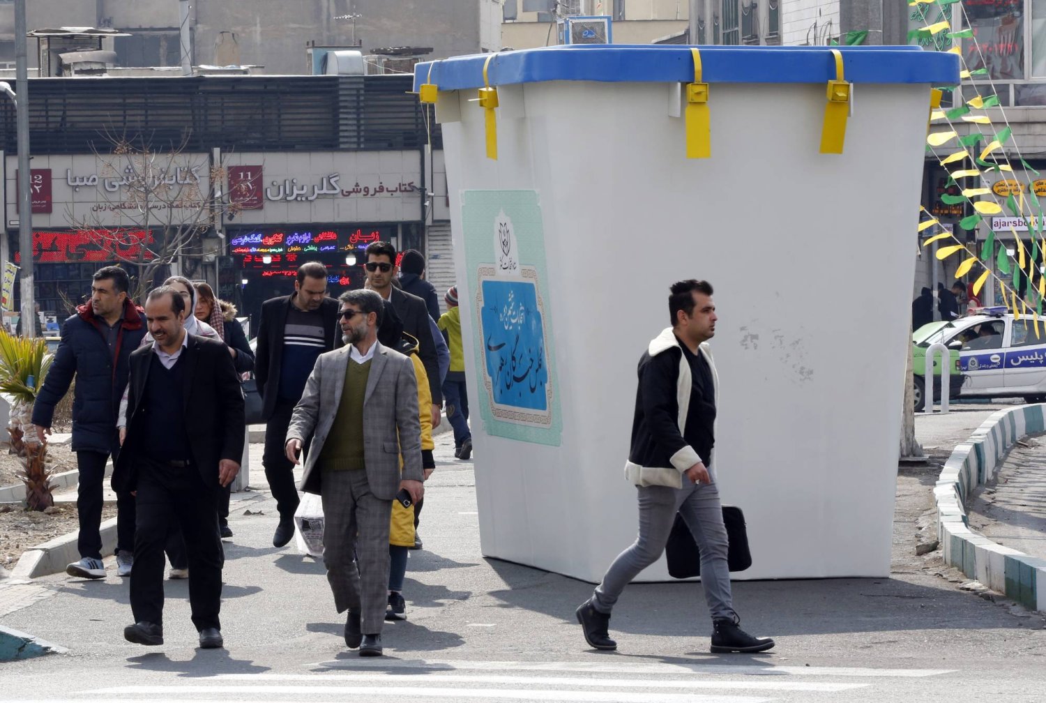 إيرانيون بجوار مجسم لصندوق الاقتراع الانتخابي خلال اليوم الأول من الحملات الانتخابية البرلمانية الإيرانية في أحد شوارع طهران (إ.ب.أ)