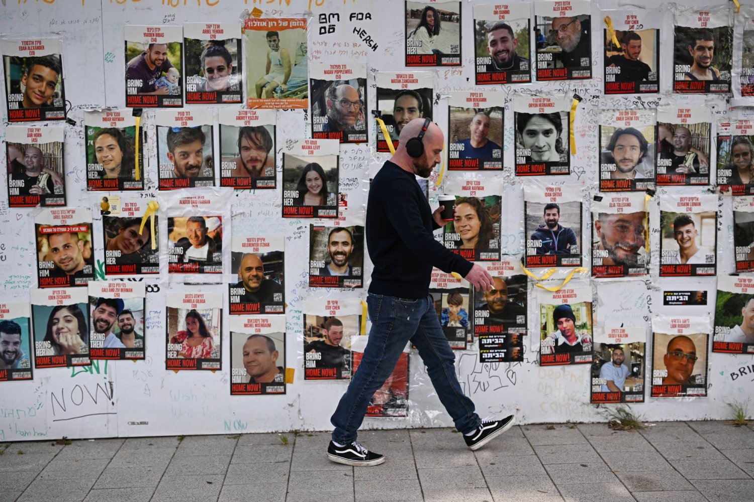 رجل يسير بجوار لافتات تعرض صور الرهائن الإسرائيليين الذين اختطفتهم «حماس» في هجومها على جنوب إسرائيل 7 أكتوبر 2023... الصورة في تل أبيب 22 فبراير 2024 (رويترز)