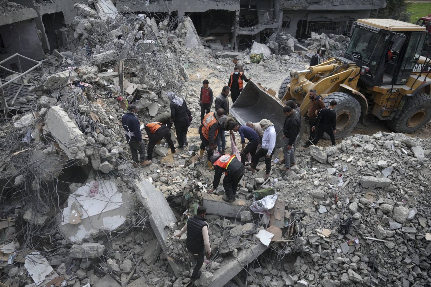 فلسطينيون يبحثون عن ناجين بعد غارة جوية إسرائيلية على مبنى سكني لعائلة ياغي في دير البلح قطاع غزة (أ.ب)