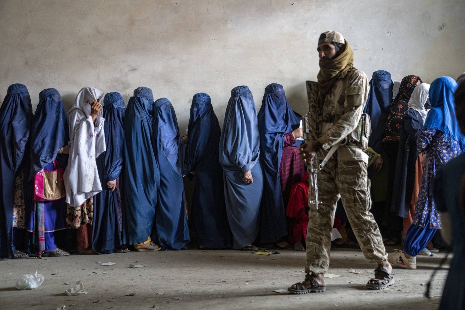 مقاتل من «طالبان» يحرس نساءً خلال تلقي الحصص الغذائية التي توزعها مجموعة مساعدات إنسانية في كابل في 23 مايو 2023 (أ.ب)