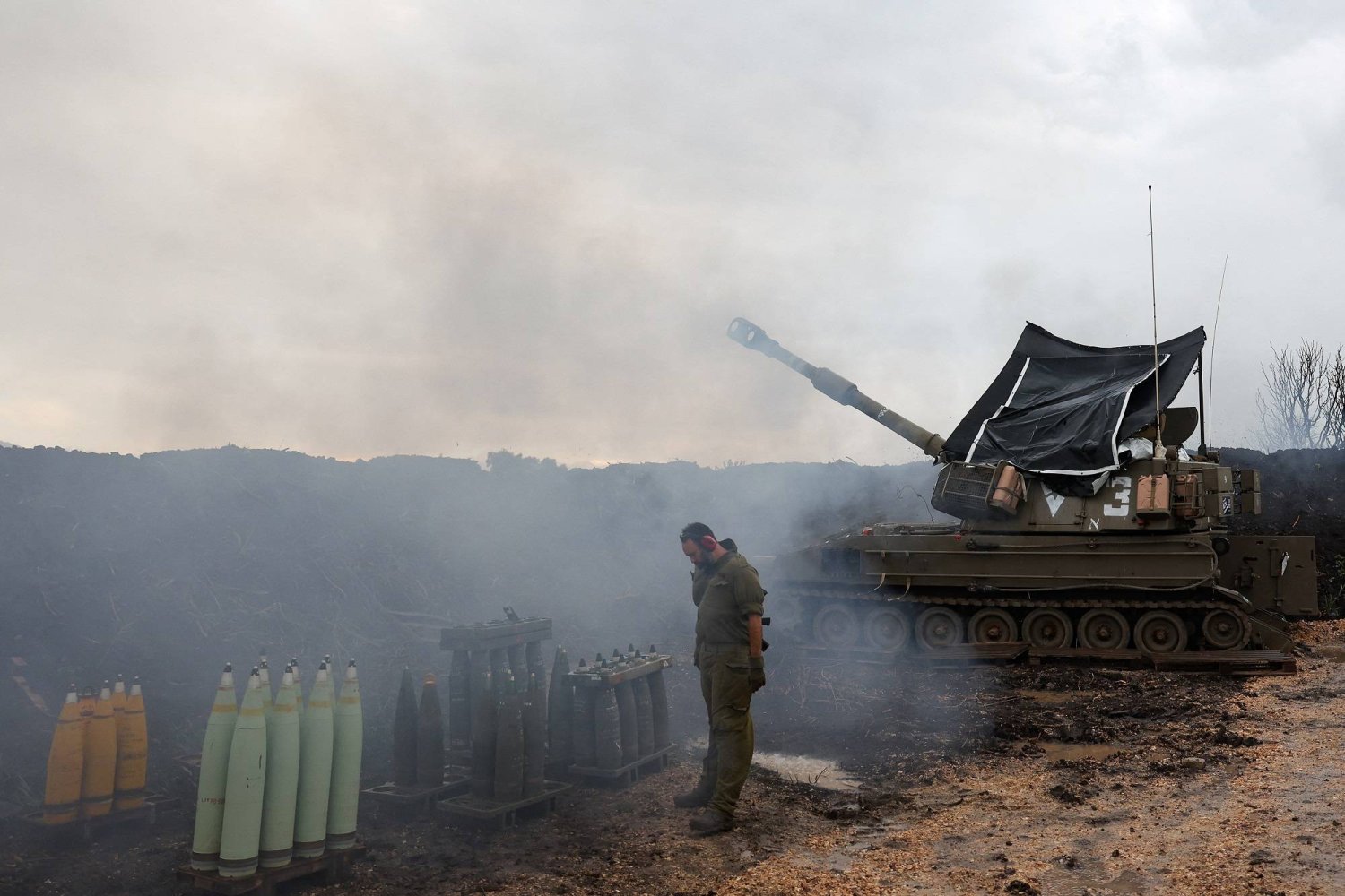 جندي إسرائيلي يقف بجوار وحدة مدفعية بالقرب من الحدود مع لبنان (رويترز)