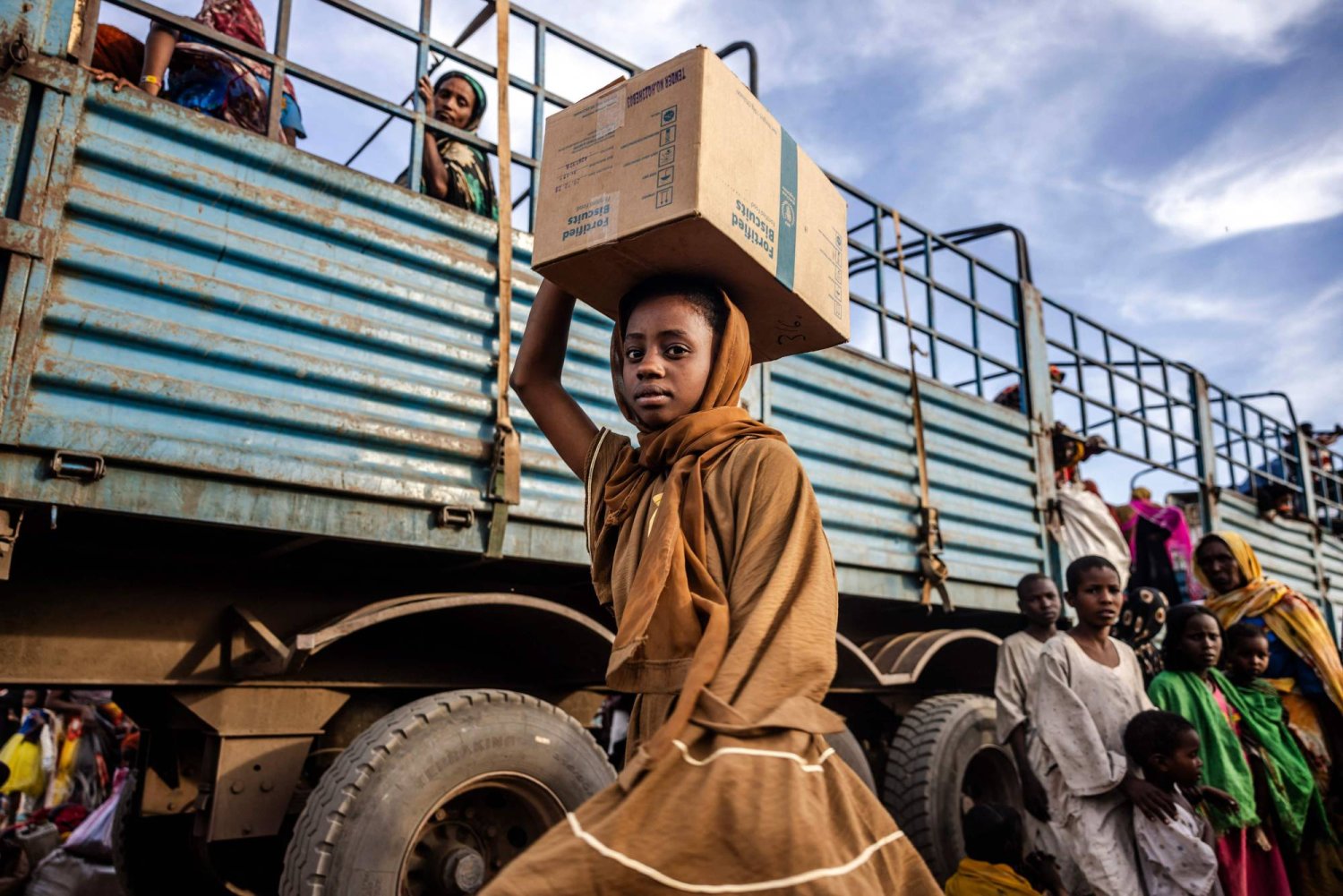 فتاة سودانية هاربة من الحرب تحمل على رأسها بعض حاجياتها (أ.ف.ب)