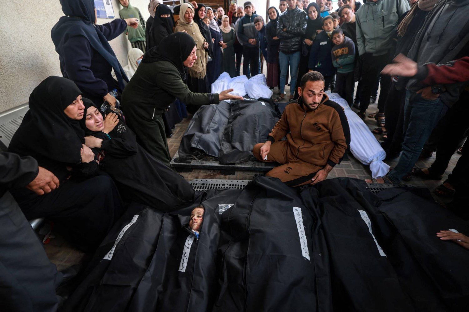فلسطينيون يبكون بالقرب من جثامين أقاربهم الذين قتلوا في غارات جوية إسرائيلية على مخيم رفح للاجئين جنوب قطاع غزة (أ.ف.ب)