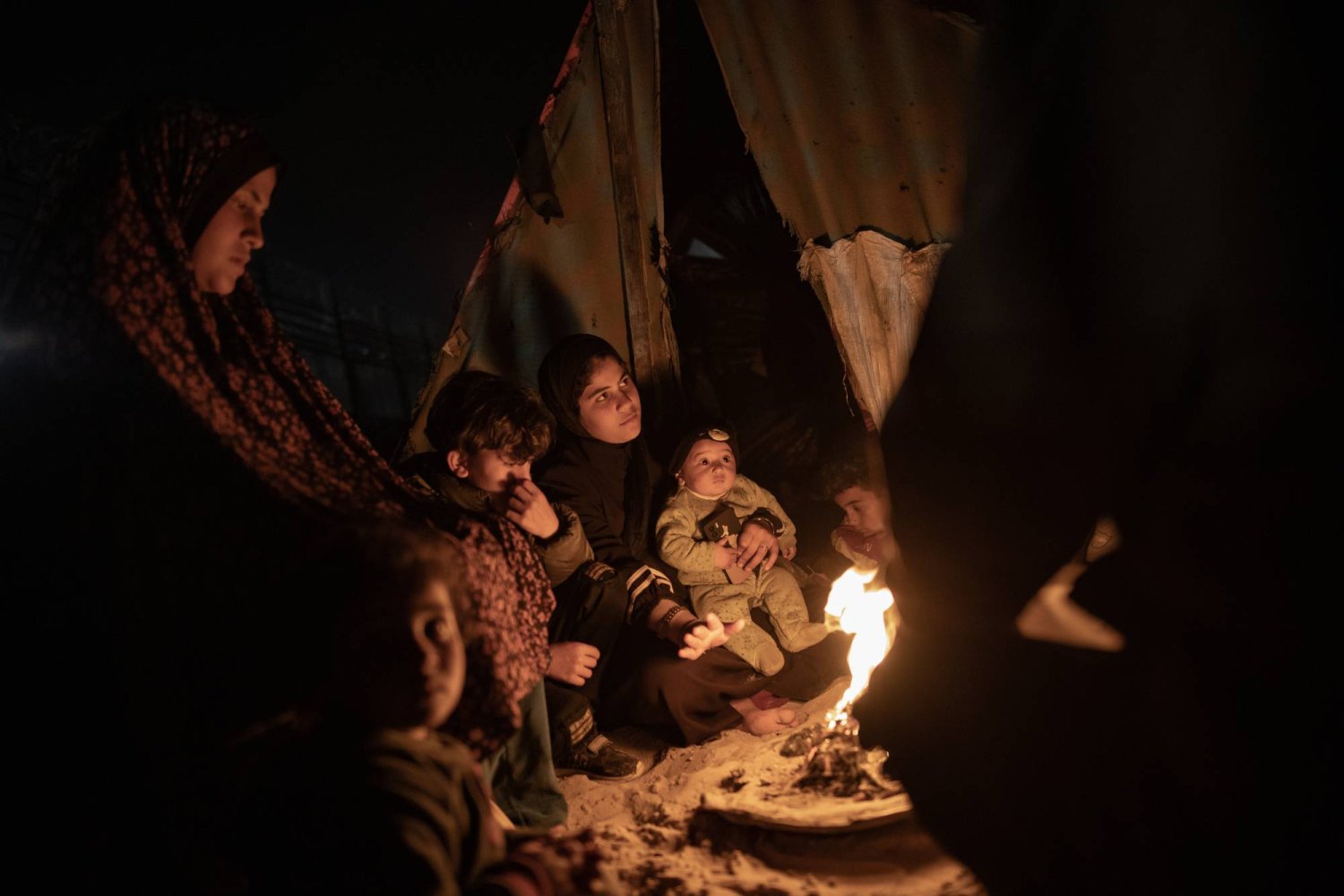 أسرة فلسطينية تلتف حول النار خارج خمية بالقرب من الحدود مع مصر