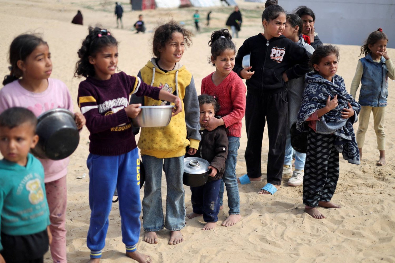 أطفال فلسطينيون ينتظرون الحصول على مواد غذائية في مخيم رفح (رويترز)