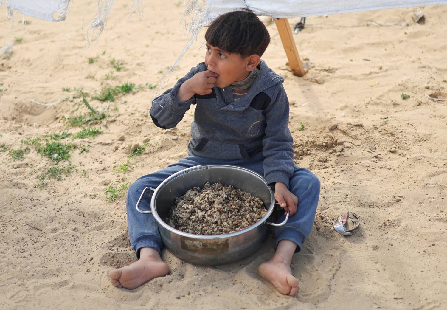 طفل يتناول الطعام في مخيم للنازحين في رفح (رويترز)