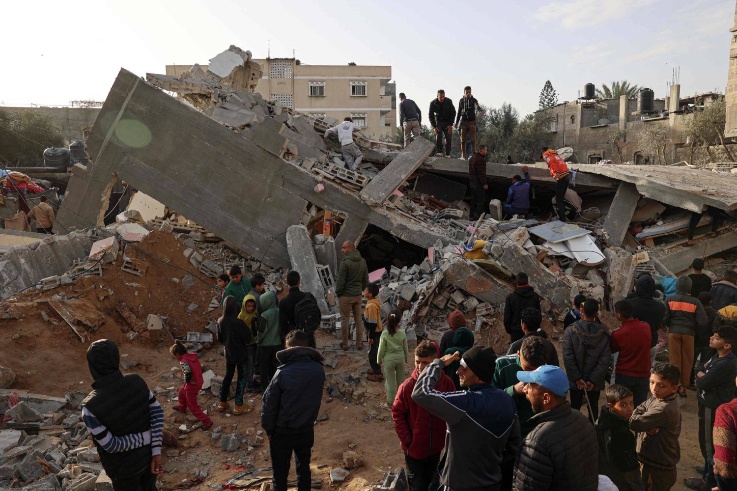 فلسطينيون يتفقدون أنقاض منزل دمرته غارة إسرائيلية في رفح (أ.ف.ب)